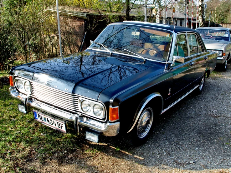 an old black car is parked in the street