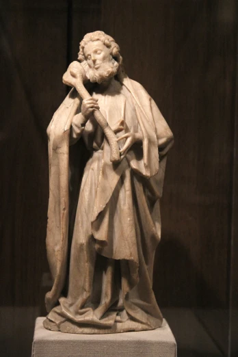 an old statue of a saint with a crucifix in his hands