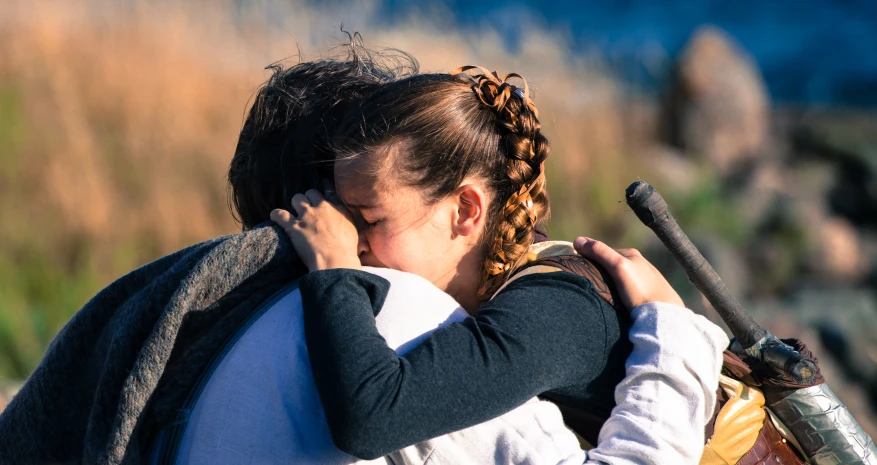 the woman is hugging her daughter outside