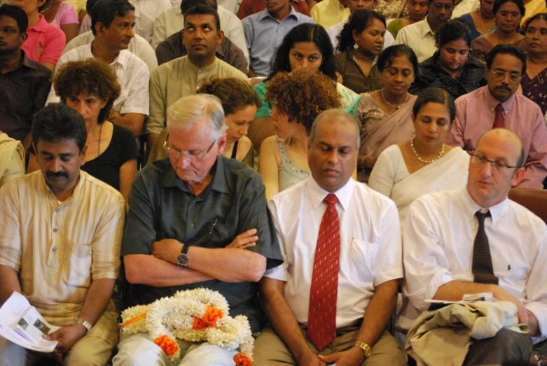 group of people sitting in a room with the heads and shoulders crossed