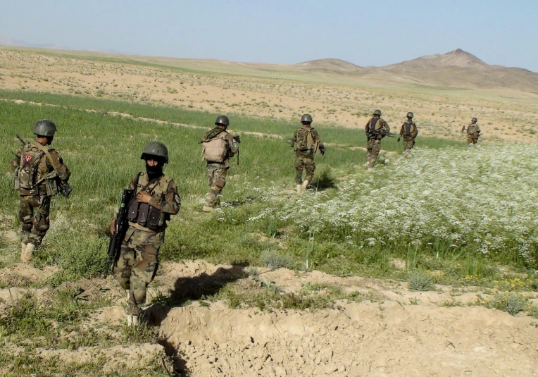 soldiers walking up a hill in camouflage