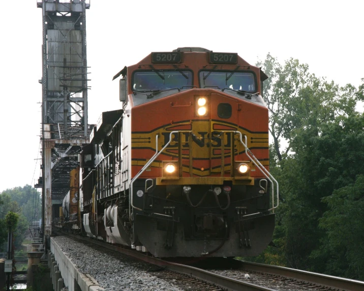 an orange and yellow locomotive going down the track