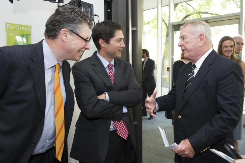 three men in business suits and ties holding hands with one another