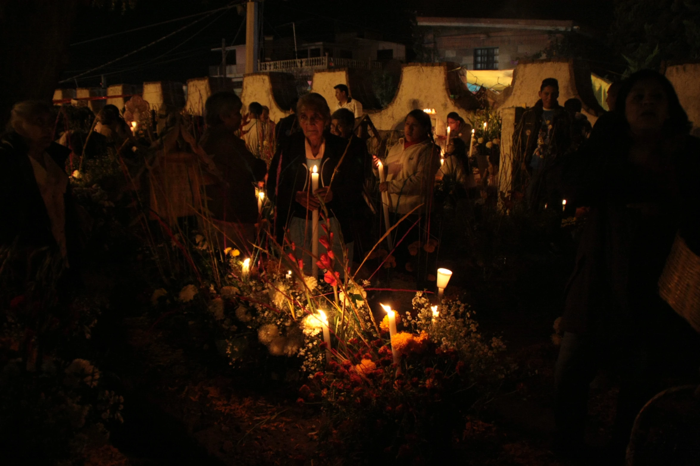 many people stand in the dark with candles burning