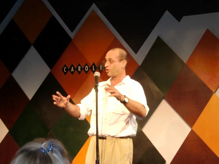 man in white shirt and shorts speaking on stage