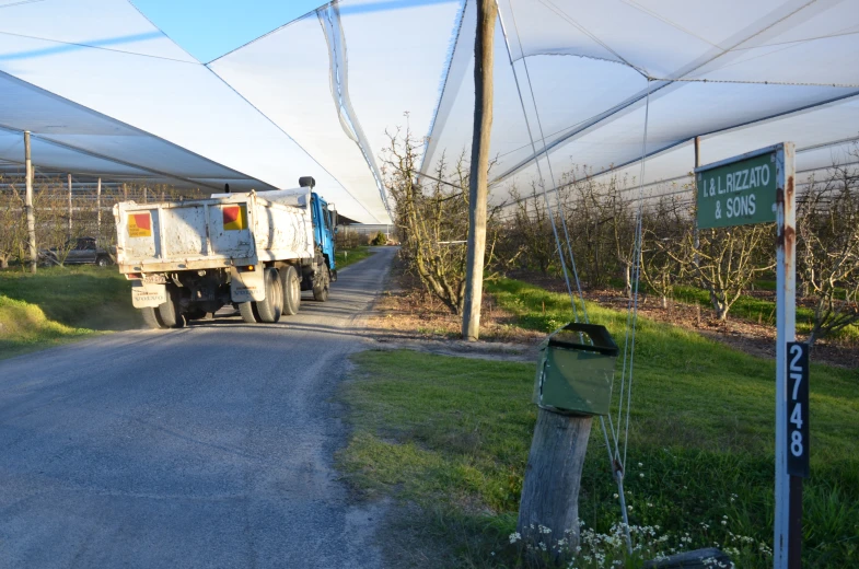 truck next to road with white shade structure and sidewalk