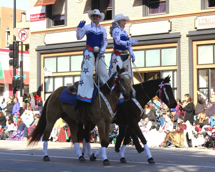 men in mexican dress riding horses down the street