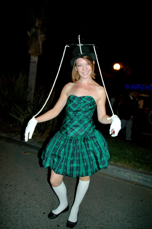 a woman is wearing an green plaid dress with white gloves and is holding an umbrella