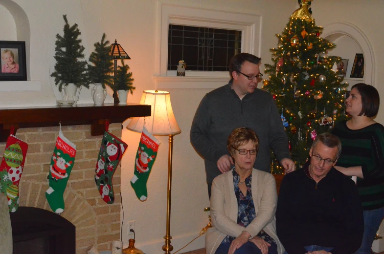 three people sitting next to a christmas tree