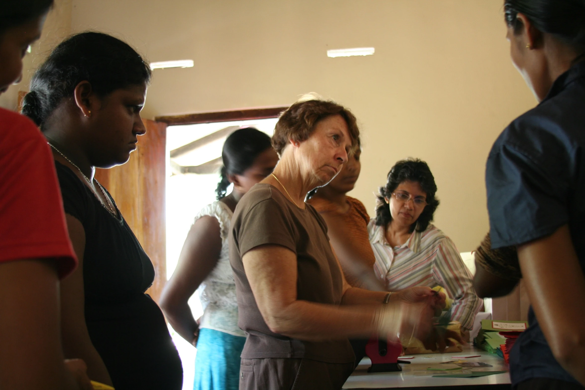 a group of women standing around a table preparing food