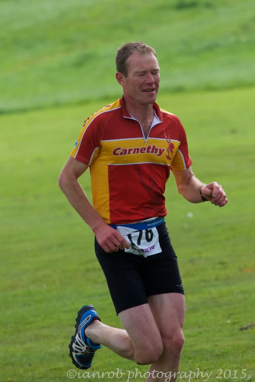 the man smiles as he runs across a grass field