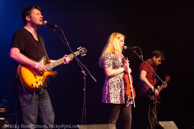 two people singing and playing guitar on stage