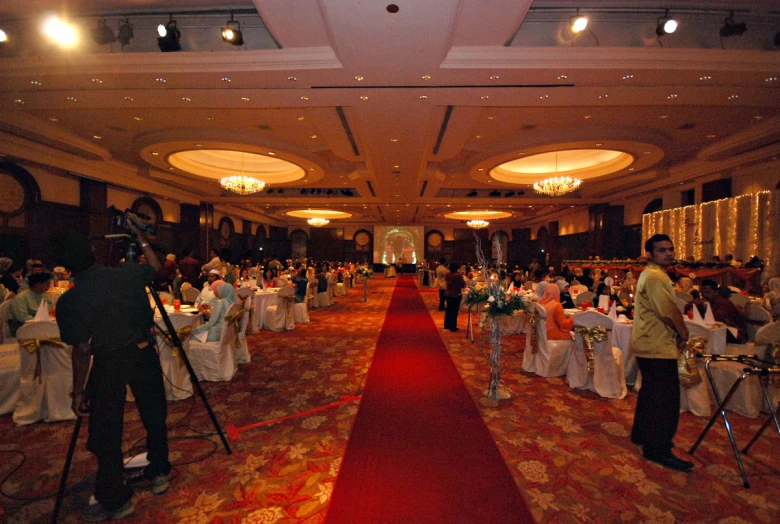 a hall set up for a party with people preparing to take pictures