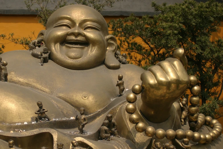 a large metal statue of a laughing buddha