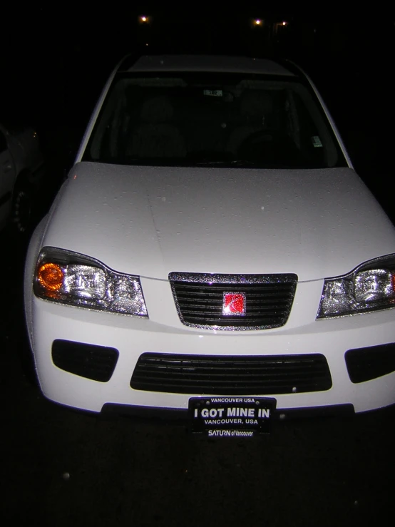 a white car is parked on a street at night