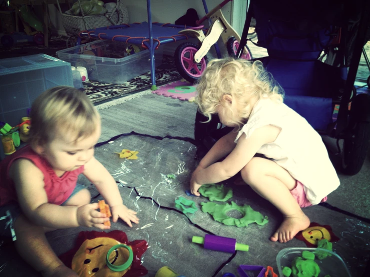 two children playing with toys in the middle of a room