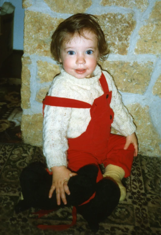 a child with an orange and black bib and red pants