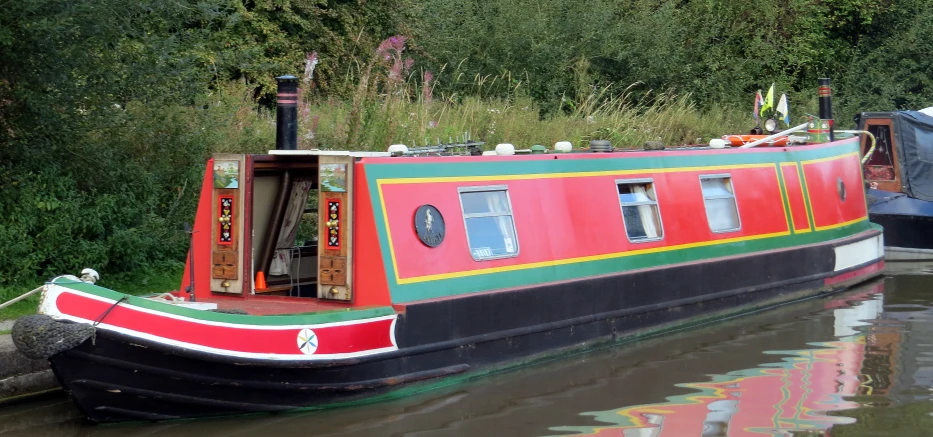 a colorful boat is on the water surrounded by grass