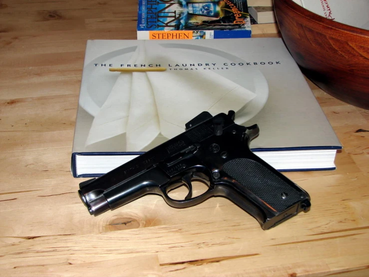 a small revolver and book on top of a table