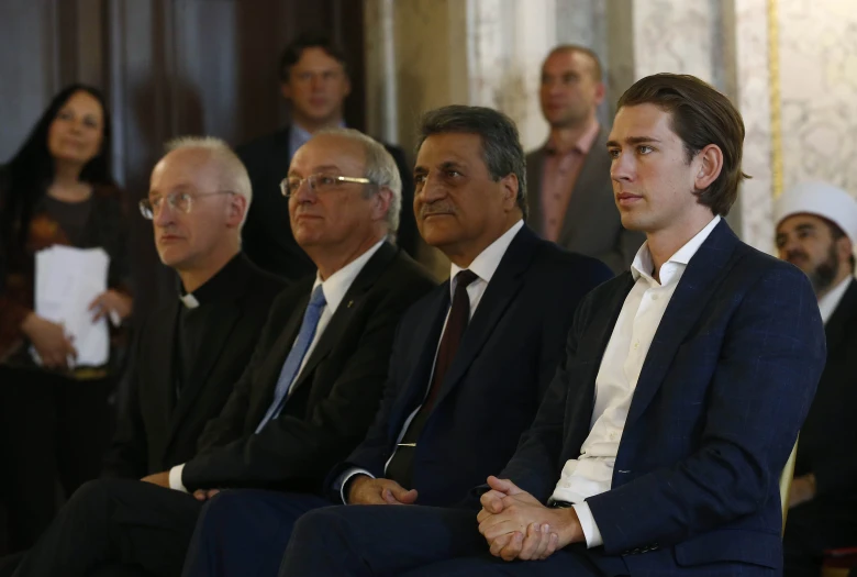 group of well dressed men sitting down in the dark