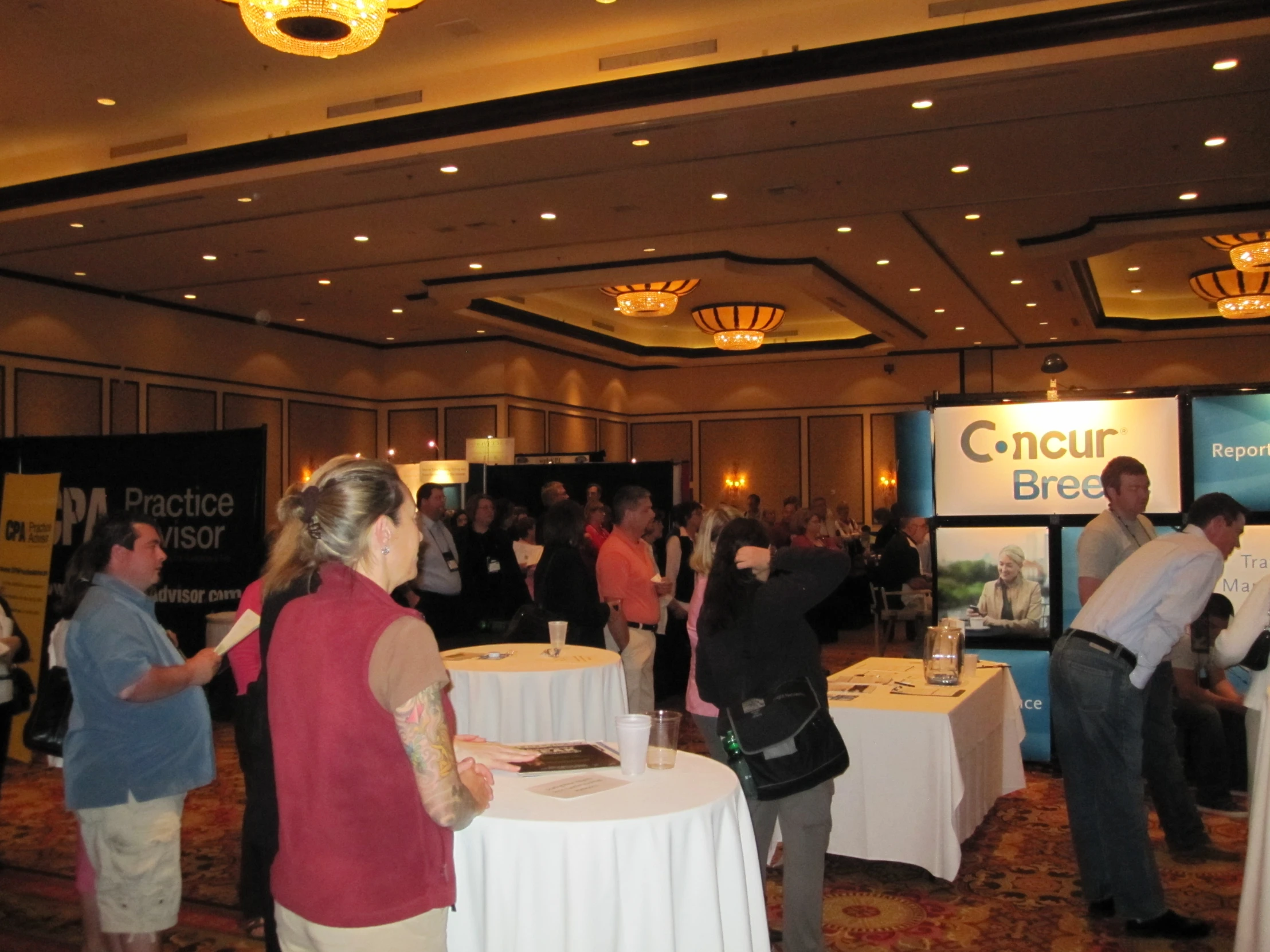 a group of people standing around tables at a conference