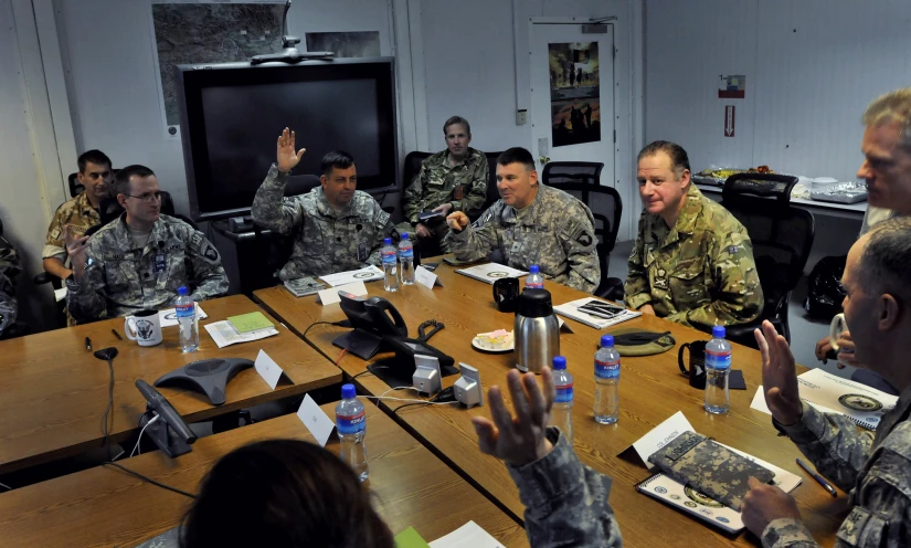 military personnel are sitting at a table during a meeting