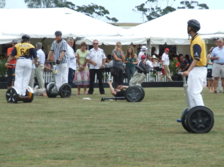 many people in an open field with one man on a small cart