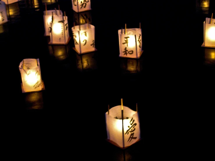 a group of lit candles in the dark with chinese characters