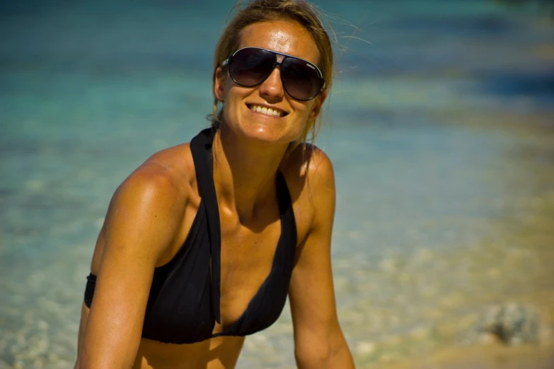 smiling woman in bikini top on beach near water