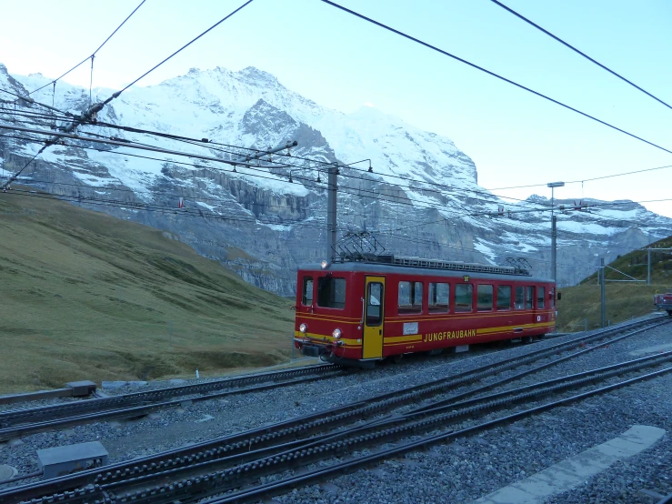 red and yellow train traveling along a mountain side