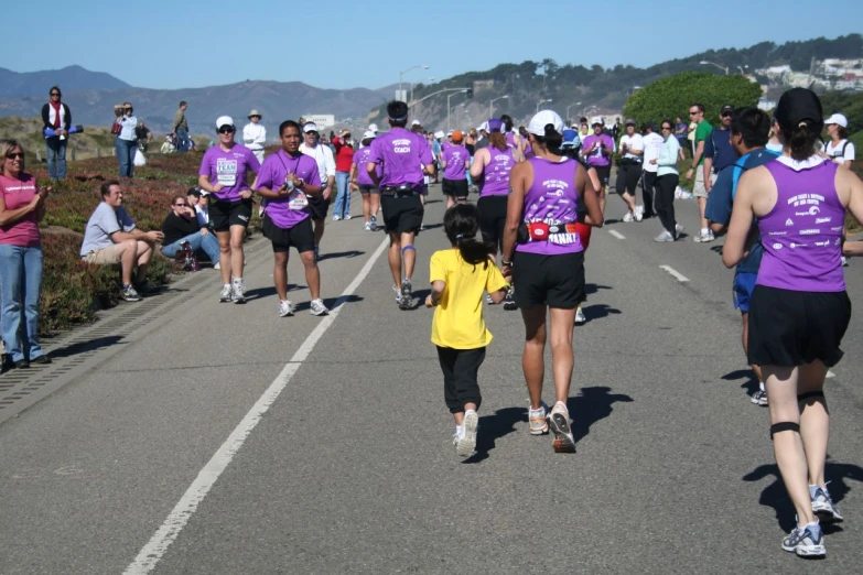 a crowd of runners run in the streets in purple shirts