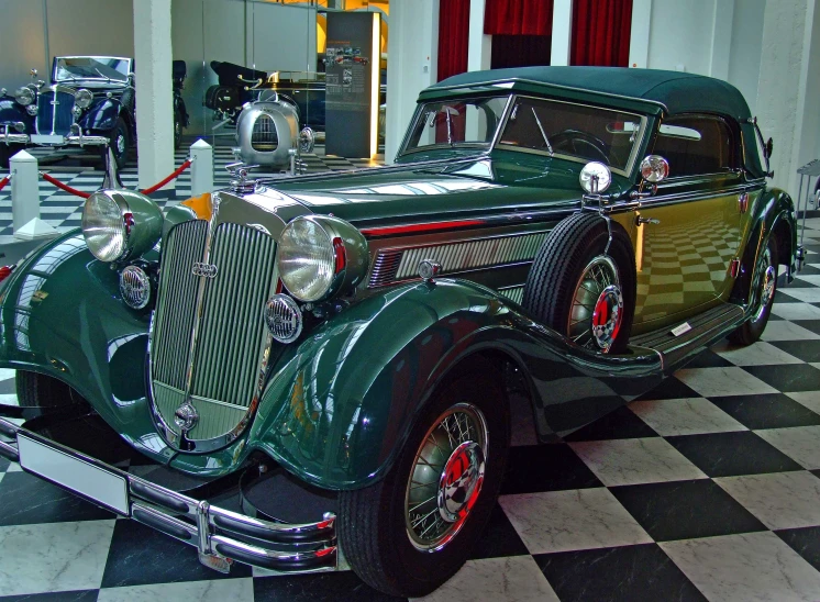 a very old car sitting on a checkered floor