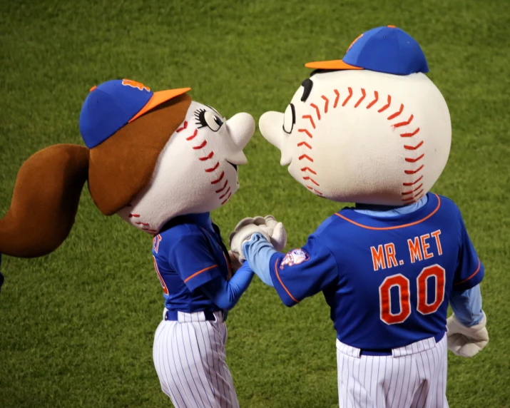 two mascots are holding hands in baseball uniforms