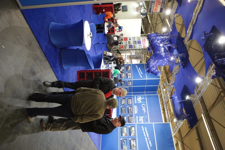 two men standing in front of a blue trade floor