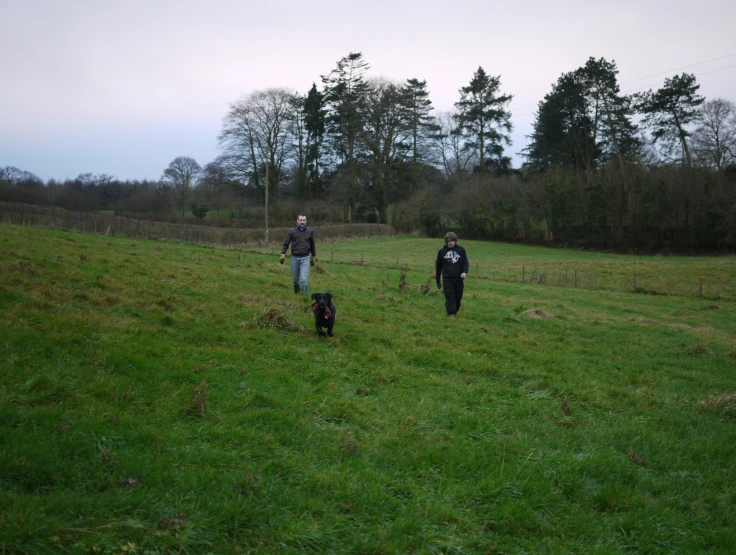 three people and a dog are in a field