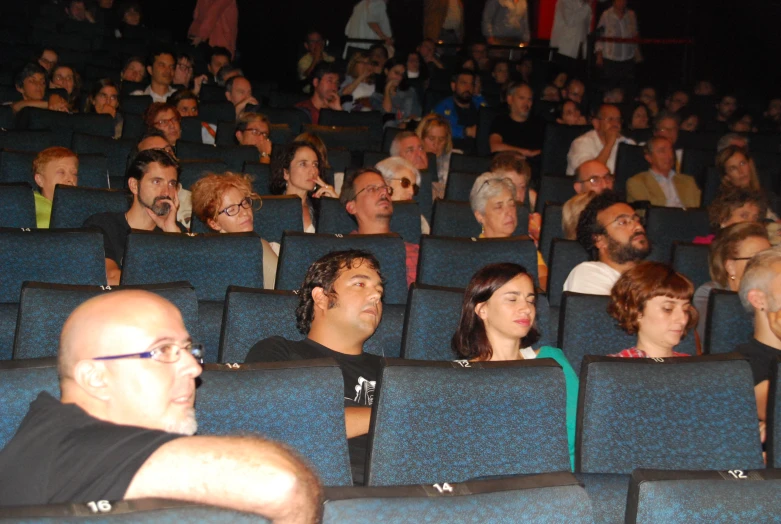 a crowd of people sitting in rows and listening to speakers