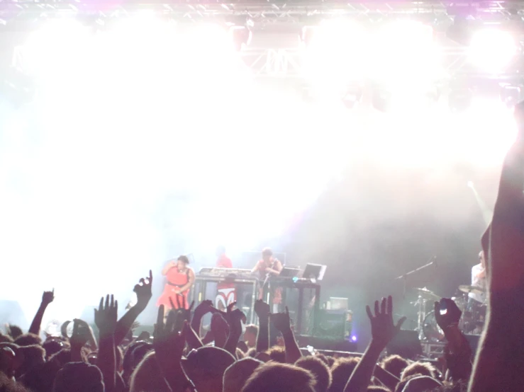 people at an outdoor concert raising their hands up in the air