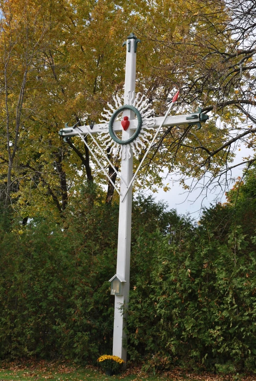 a cross sitting on the grass in front of some trees