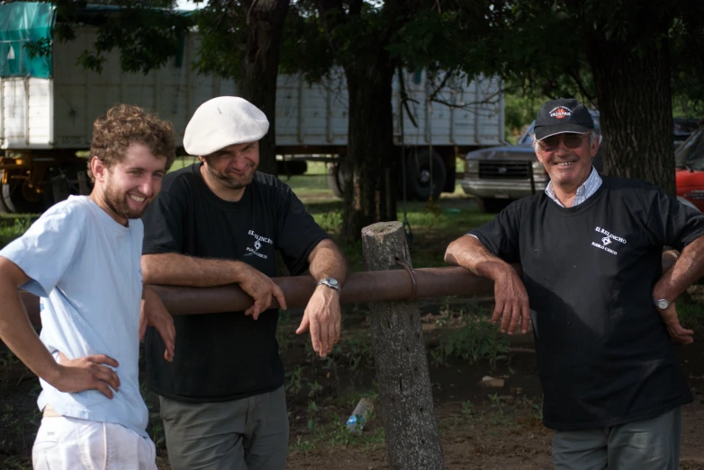 four people with one man wearing a hat posing behind a fence