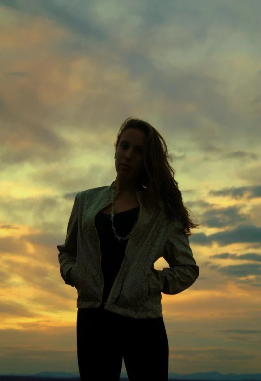 a woman standing in front of a very cloudy sky