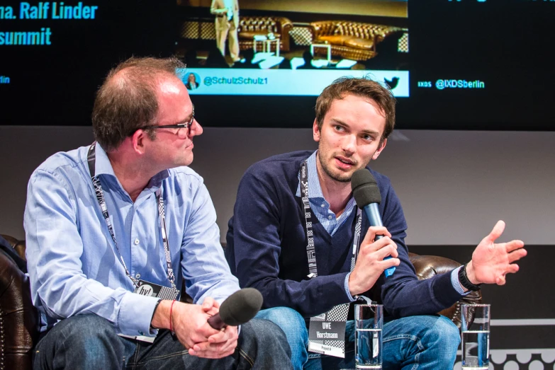 two people are sitting talking while holding microphones