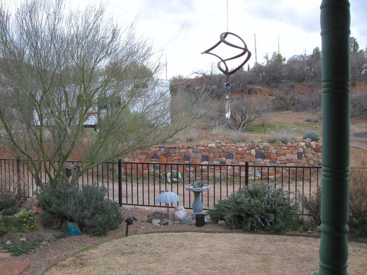 a birdbath hanging off the side of a metal fence