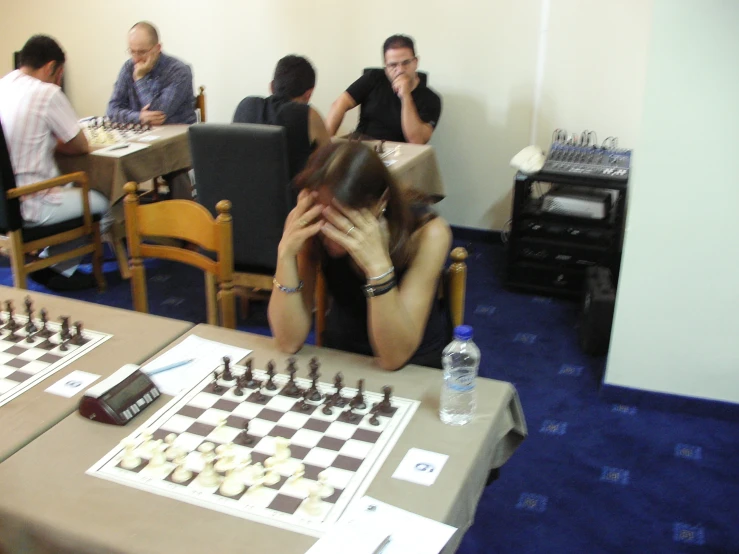 a chess player sitting on the chess board in front of other people