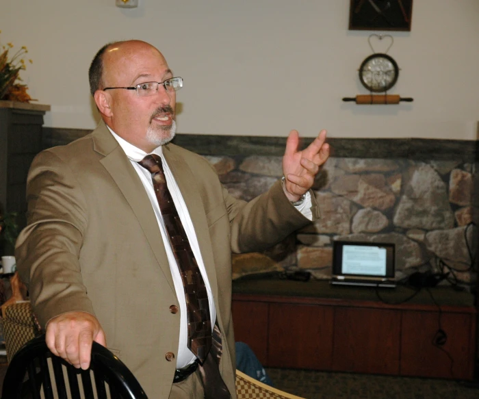 a man standing in front of a desk gesturing