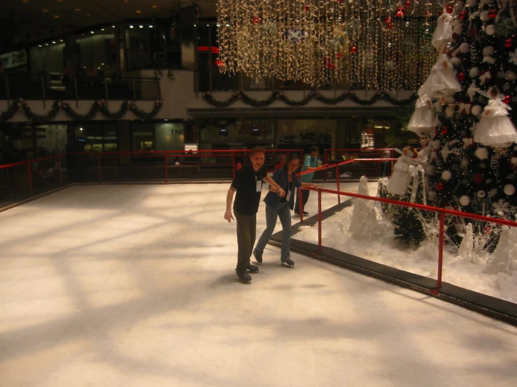 some people on a skating rink with christmas trees