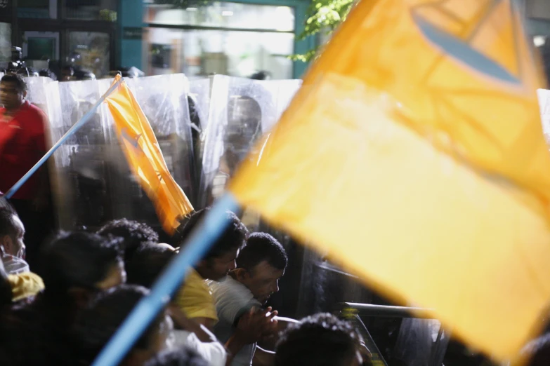 some people some orange flags some buildings and blue and yellow items