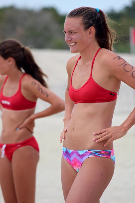 two young women in red bikinis playing volleyball