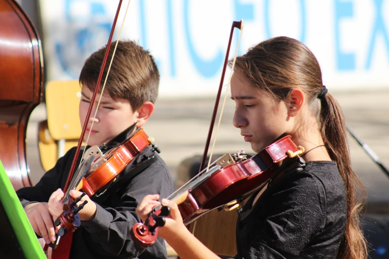 two s play violin while another looks on