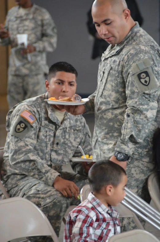 some soldiers that are eating food from plates