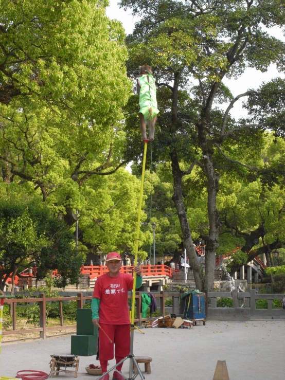 man in red shirt on bicycle by large green banner